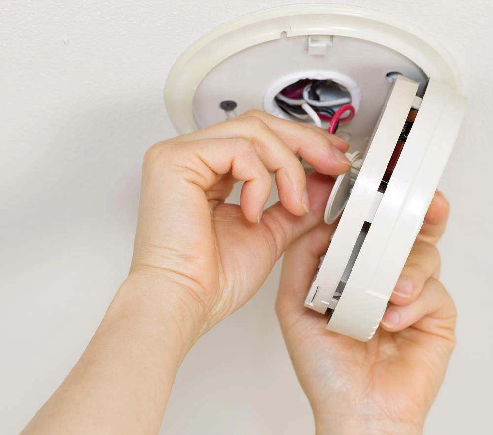 Hardwired smoke alarm being replaced on a Gold Coast ceiling