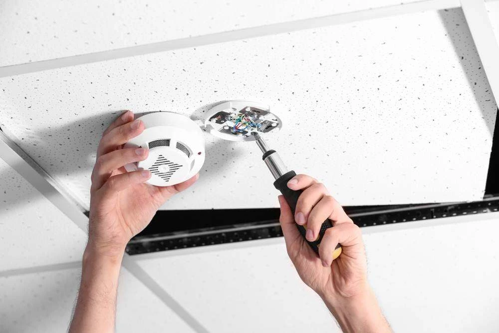 Licensed electrician installing a hardwired smoke alarm in a Gold Coast home